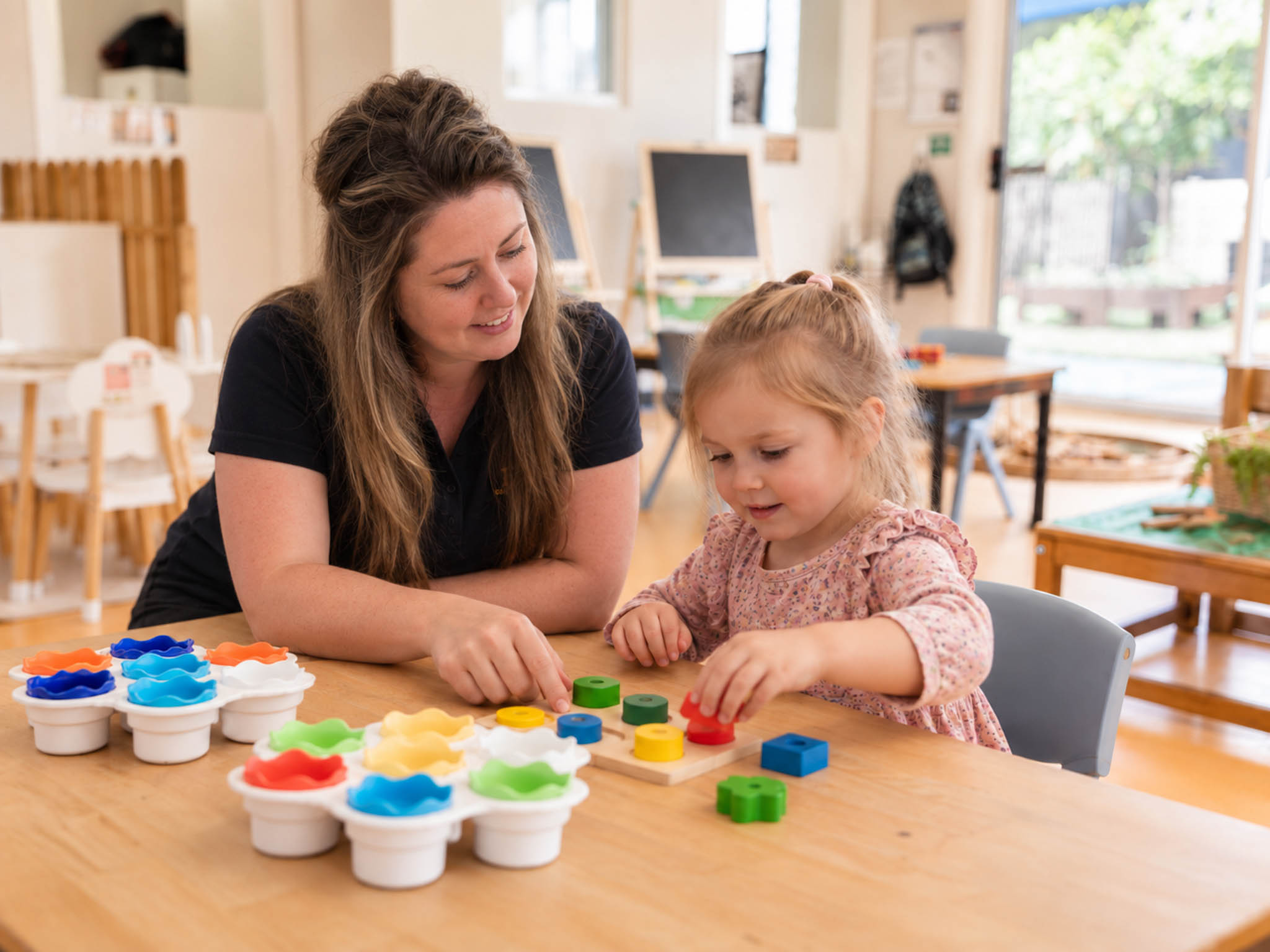 An educator helping a child explore colourful shapes