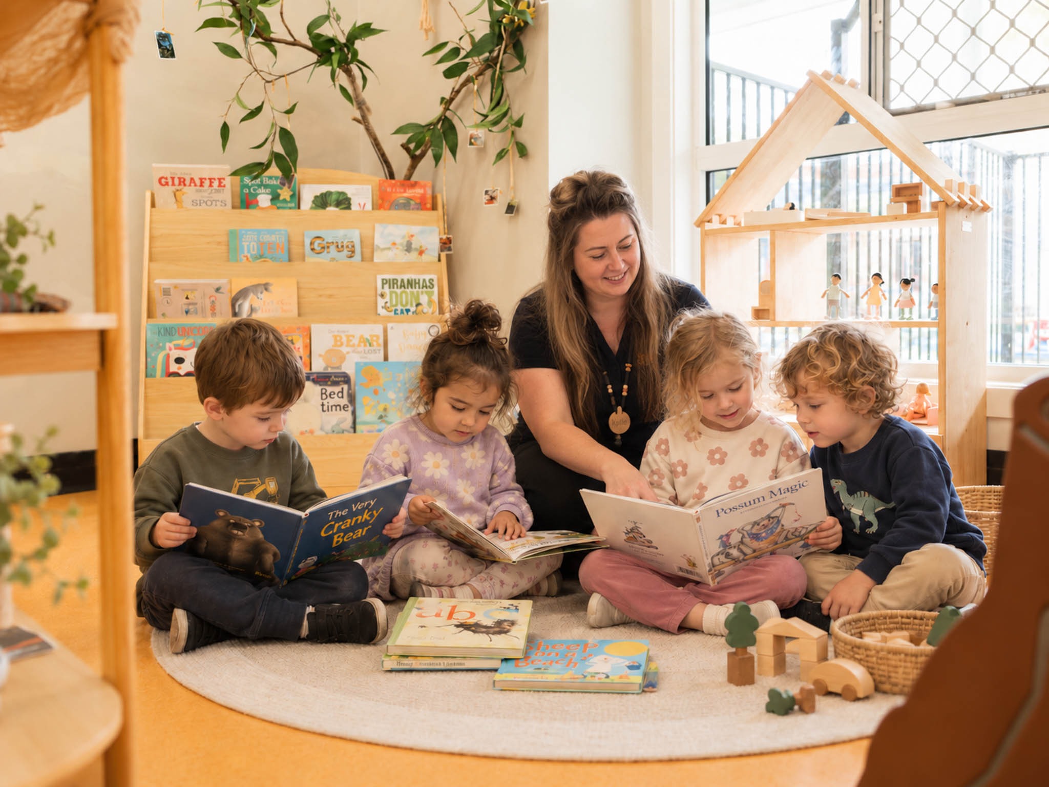 An educator and children reading together in a welcoming book corner