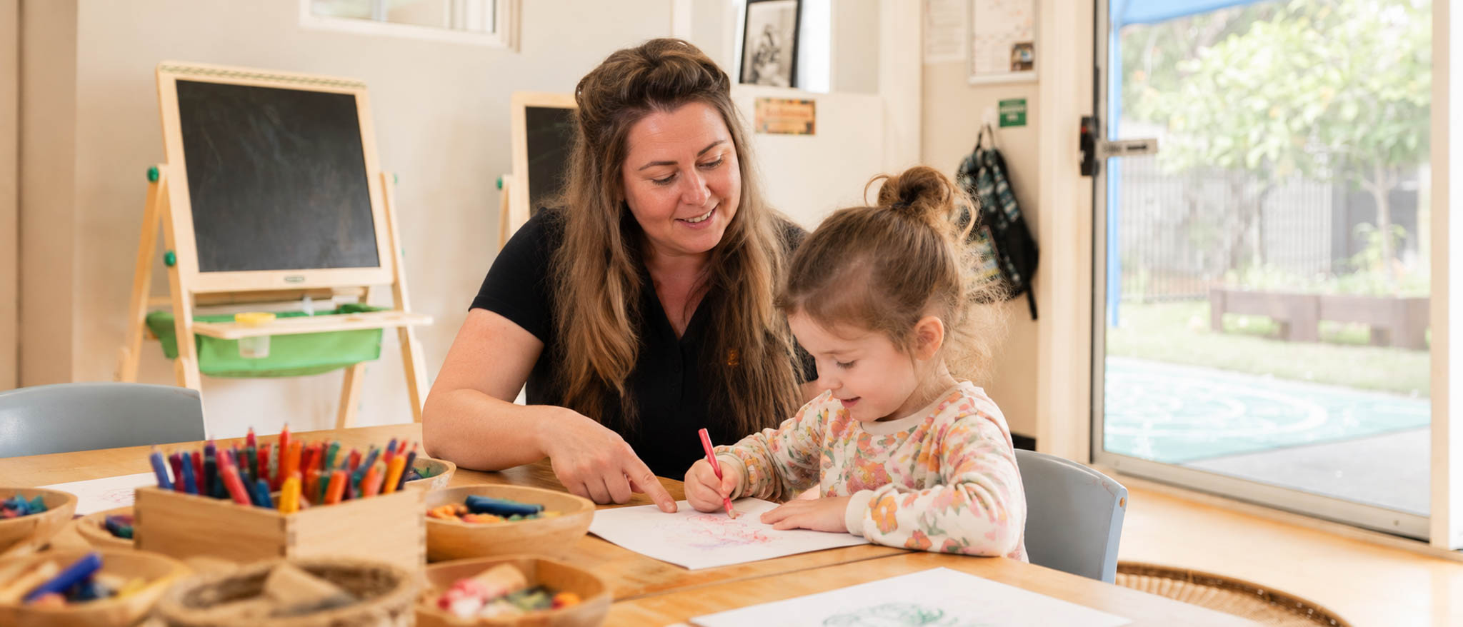 An educator and child exploring art in a bright classroom
